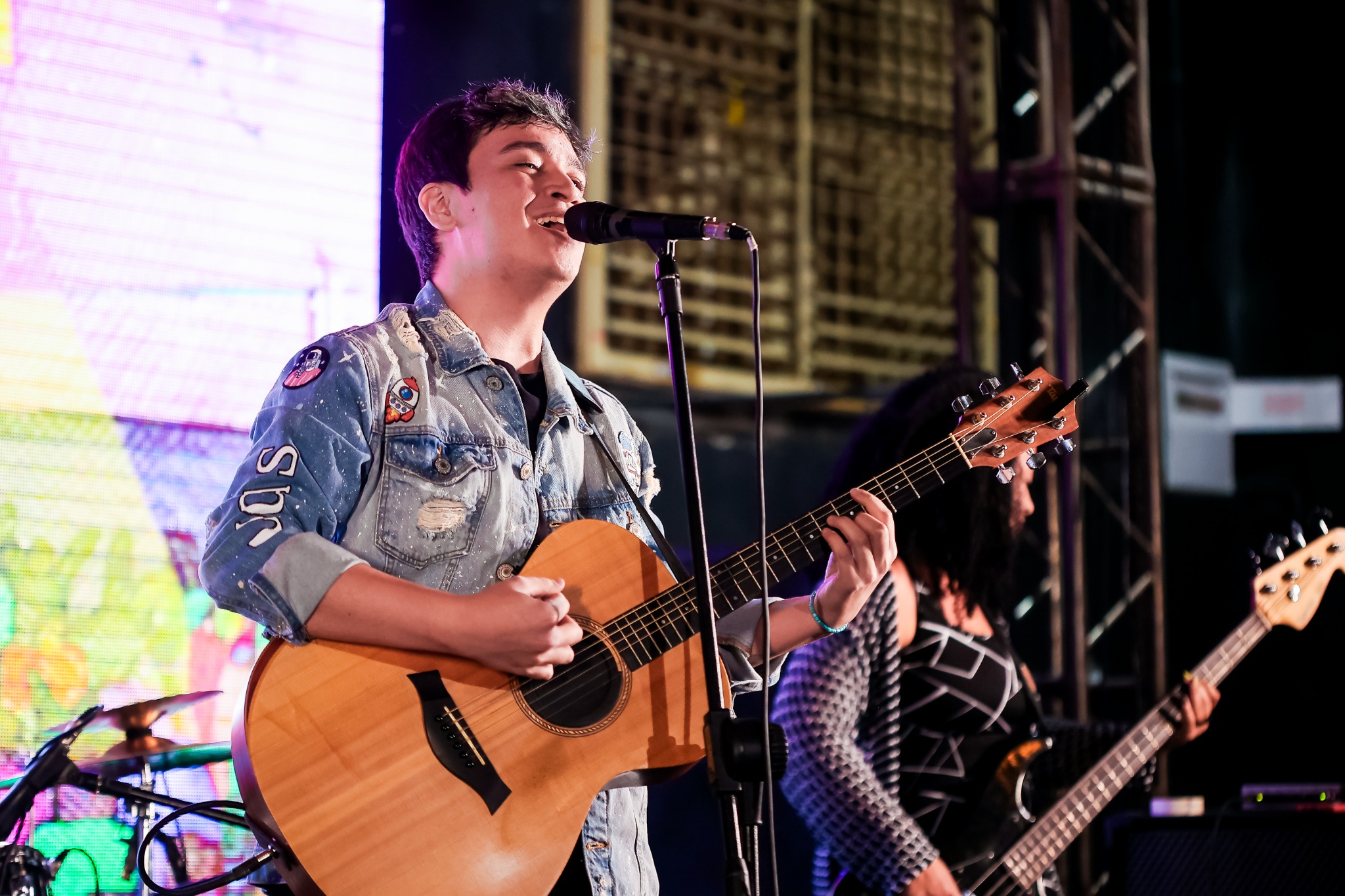 Lucas Tenguam cantando e tocando violão em uma apresentação ao vivo